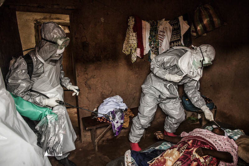 Members of a Red Cross burial team take samples from a woman suspected of dying of Ebola in the village of Dia (PHOTO: PRI.org)